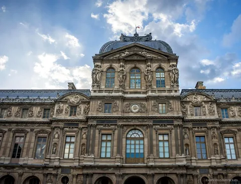 Padiglione dell'orologio del Louvre con cupola e statue sotto il cielo azzurro, meta dei biglietti Museo del Louvre