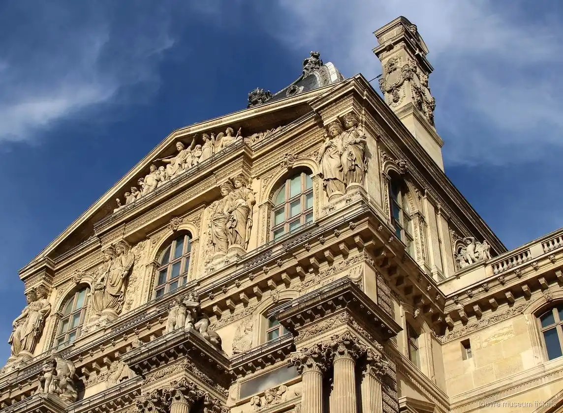 Façana esculpida del Louvre amb estàtues i frontó sota el cel blau, vista amb entrades del Museu del Louvre