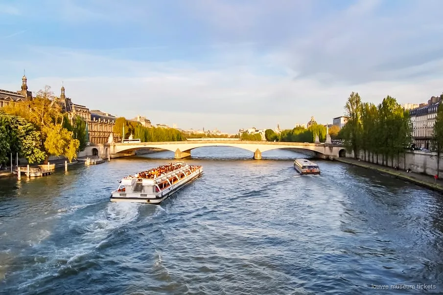 Seine river cruise boat passing Paris landmarks included with the Louvre Museum combo ticket