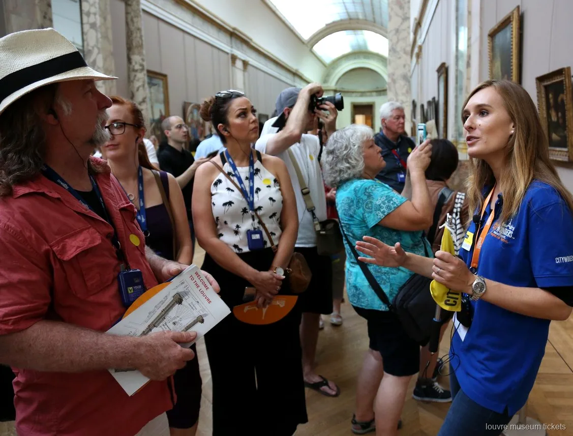 Resim galerisinde Louvre haritaları tutan gruba anlatım yapan rehber, Louvre Müzesi biletleri ile rehberli tur