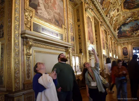Small group gazing up at the painted gilded ceiling of the Galerie d'Apollon, seen with Louvre Museum tickets